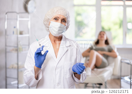 Portrait of elderly doctor with syringe. 120212171