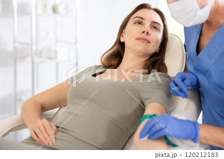 Elderly doctor drawing blood from young patient. 120212183