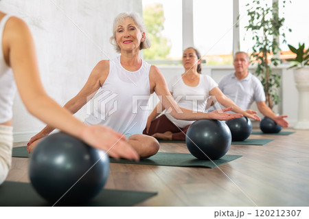 Pilates - mature women and man with soft ball at gym 120212307