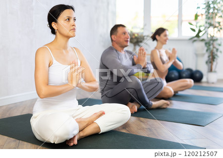 People different nationality making yoga meditation in lotus pose in fitness studio People different nationality making yoga meditation in lotus pose in fitness studio 120212507