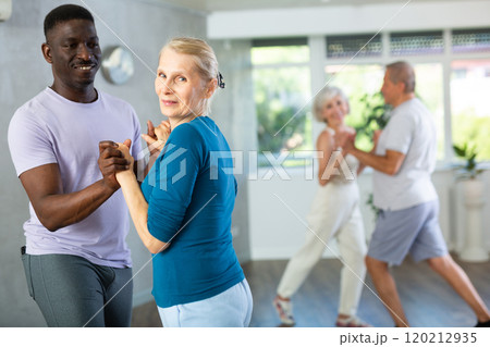 Mature men and women practicing Ballroom dances in training room Mature men and women practicing Ballroom dances in training room 120212935