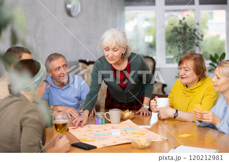 Retirees happy play board games and drink tea with cookies 120212981