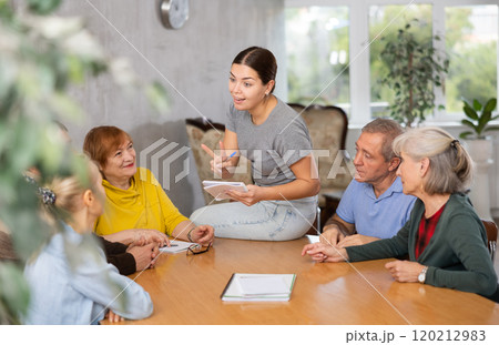 Young psychologist together with elderly adults have group therapy round table 120212983