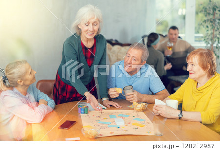 Elderly woman playing board game with friends at table Elderly woman playing board game with friends at table 120212987