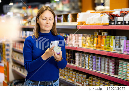 Young woman scanning label on tin can of wet food in pet store Young woman scanning label on tin can of wet food in pet store 120213073