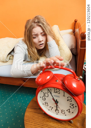 Woman waking up turning off alarm clock in morning 120213604