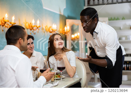 Waiter serving two women at the restaurant 120213694