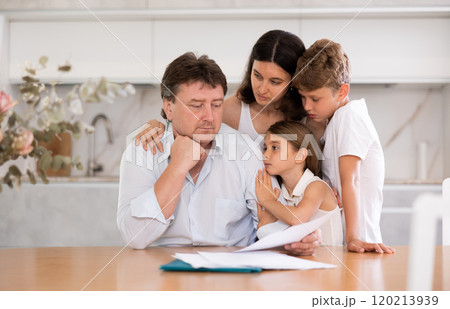 Wistful father looking through papers with familyの写真素材 [120213939] - PIXTA