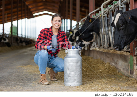 Positive young woman farmer squatting at milk can Positive young woman farmer squatting at milk can 120214169