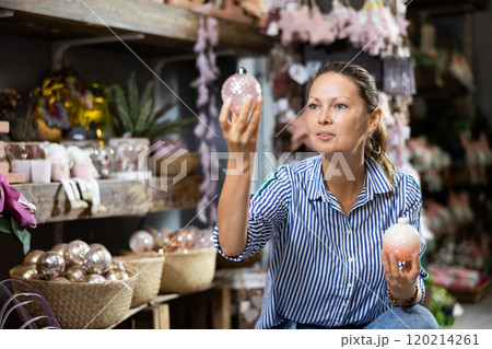 Cheerful lady in casual shirt buying Christmas bulbs before holidays in a store Cheerful lady in casual shirt buying Christmas bulbs before holidays in a store 120214261