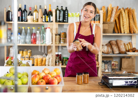 Young female seller offering lentils in grocery store 120214302