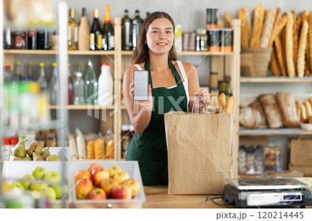 Girl supermarket seller holding smartphone in hand showing screen Girl supermarket seller holding smartphone in hand showing screen 120214445
