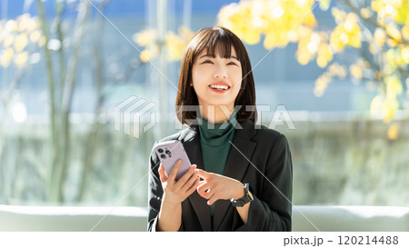 笑顔でスマホを使う若い女性・ビジネスウーマン 120214488