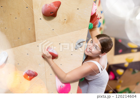 Sporty woman exercising on wall in climbing gym during bouldering training 120214604