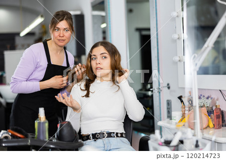 Female hairdresser offering hairstyling to young girl client Female hairdresser offering hairstyling to young girl client 120214723