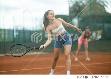 Two young women playing doubles tennis 120214826