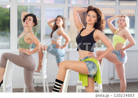 Group of women in high heels rehearsing dance with their feet on chair Group of women in high heels rehearsing dance with their feet on chair 120214883