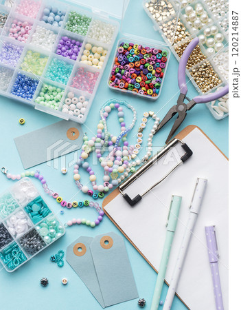 Colorful beads, pliers, clipboard and price tags arranged on blue surface for diy bracelet making 120214887