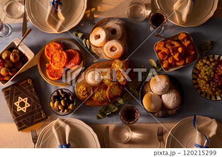 Top down shot of served table with traditional Jewish treats and Torah with star of David on cover 120215299