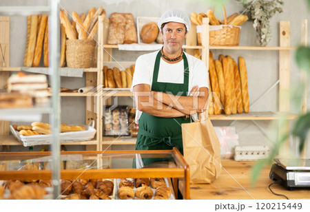 Middle-aged male seller stands in bake house, ready to greet customers Middle-aged male seller stands in bake house, ready to greet customers 120215449