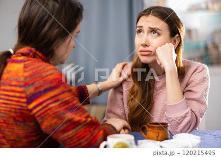 Woman complains to her friend about life while sitting at table with cups of tea Woman complains to her friend about life while sitting at table with cups of tea 120215495