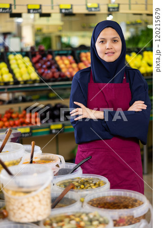 Young woman in hijab selling olives in supermarket Young woman in hijab selling olives in supermarket 120215679