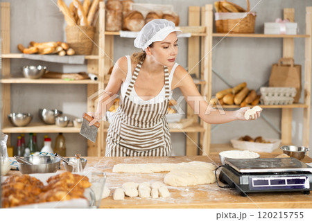 Woman baker cuts and weighs pieces of dough 120215755