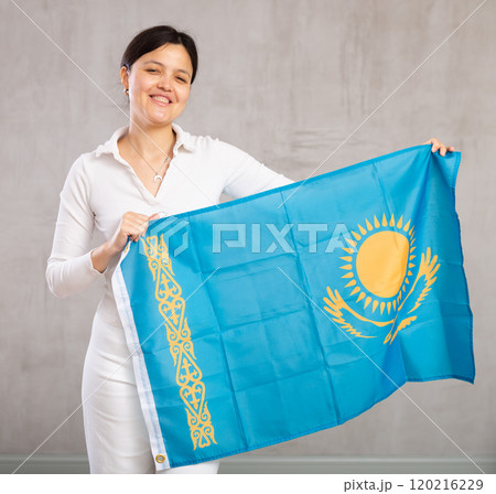 Middle-aged woman in casual clothes holds unfurled flag of Kazakhstan in hands raised above head Middle-aged woman in casual clothes holds unfurled flag of Kazakhstan in hands raised above head 120216229