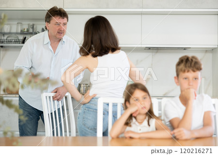 Angry parents quarrelling in the kitchen and children sitting at the table Angry parents quarrelling in the kitchen and children sitting at the table 120216271