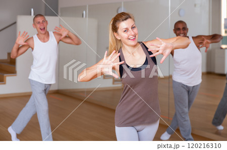 Young woman enjoying active dance with group in choreographic studio 120216310