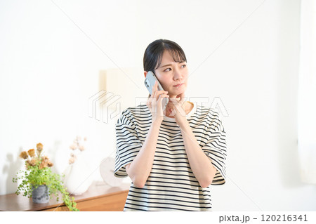 リビングで通話をする若い女性　リビング　ワンルーム 120216341