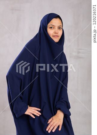 Portrait of young smiling woman in hijab posing in studio 120216371