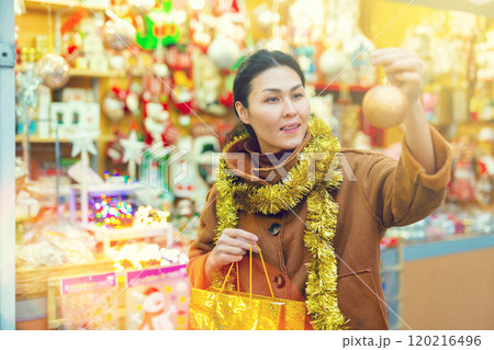 Asian female choosing decorations at Christmas fair 120216496