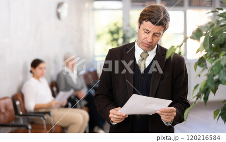 Adult man posing with documents in office 120216584