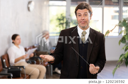 Affable secretary man stands at entrance to office reception and expects visitors 120216592