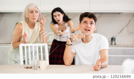 Upset and unhappy son-in-law sitting in the kitchen separately, family conflict 120216699