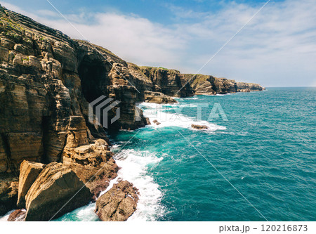 Spectacular rocky coastline with towering cliffs and turquoise ocean waves Spectacular rocky coastline with towering cliffs and turquoise ocean waves 120216873