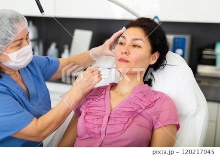 Woman getting injection for facial correction procedure in clinic Woman getting injection for facial correction procedure in clinic 120217045