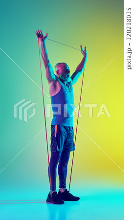 training with resistance band against gradient green yellow background in neon light training with resistance band against gradient green yellow background in neon light 120218015