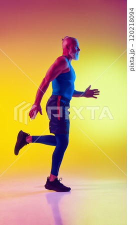 Full-length side view image of muscular elderly man in sportswear in motion, training against gradient yellow background in neon light Full-length side view image of muscular elderly man in sportswear in motion, training against gradient yellow background in neon light 120218094