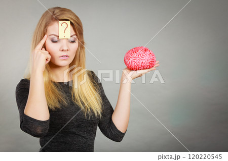 Woman thinking and holding fake brain 120220545