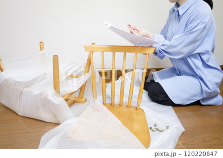 通販で購入した椅子を組み立てるために取扱説明書を読む女性 120220847