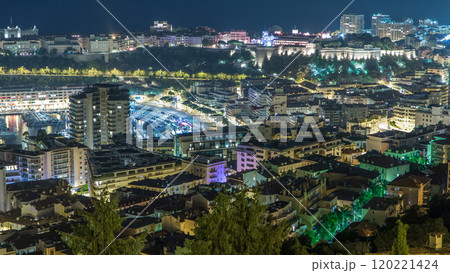 Cityscape of Monte Carlo, Monaco night timelapse with roofs of buildings and traffic on roads. 120221424