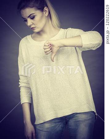 Sad woman showing thumb down gesture Sad woman showing thumb down gesture 120222619
