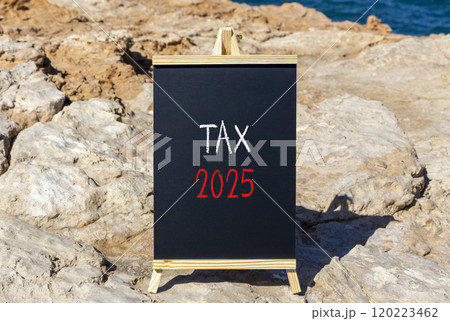Planning tax 2025 new year symbol. Concept words Tax 2025 on beautiful yellow chalk blackboard. Beautiful stone beach blue sky background. Business tax 2025 new year concept. Copy space. 120223462
