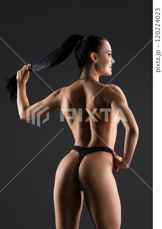 Fitness model topless rearview against gray background 120224023