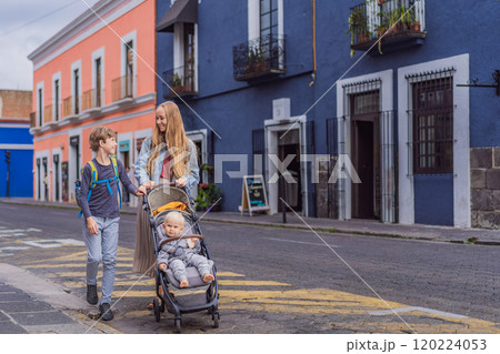 Mother tourist with her toddler and teenage sons walking through the colorful colonial streets of Puebla, Mexico. Travel, cultural exploration, and vibrant architecture concept Mother tourist with her toddler and teenage sons walking through the colorful colonial streets of Puebla, Mexico. Travel, cultural exploration, and vibrant architecture concept 120224053