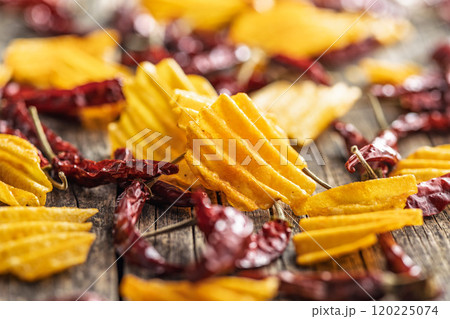 Crispy potato chips and chili peppers on wooden table. 120225074