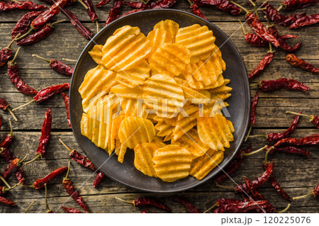 Crispy potato chips on plate on wooden table. Top view. 120225076