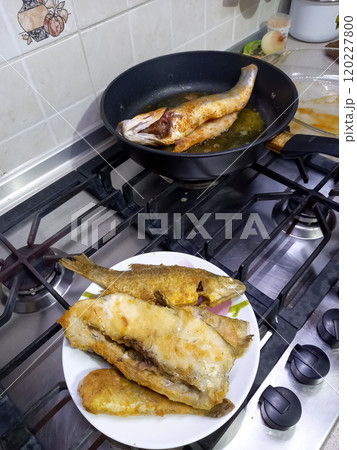 fried fish lies on a plate and in a frying pan fried fish lies on a plate and in a frying pan 120227800